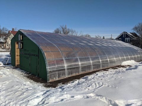 A farm scale winter greenhouse surrounded by snow.