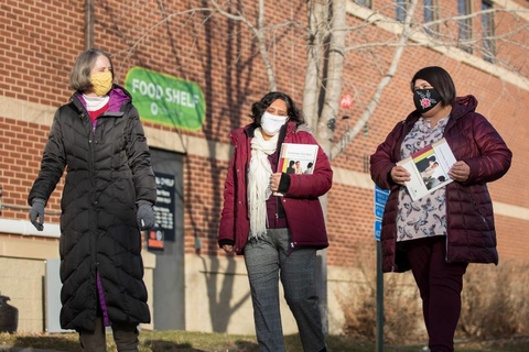 Three masked women walk outside a local food shelf,