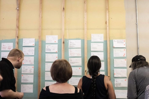 People standing in front of a wall of ideas placing a sticker for their vote.