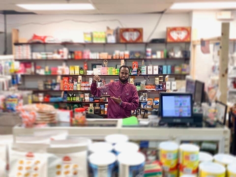 Abdi Yusuf holding an award while standing in his grocery store.
