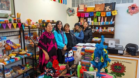 Five women standing together in a row in a store filled with colorful items.