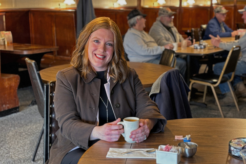 Amy Johnson sentada en una mesa de café con una taza de café