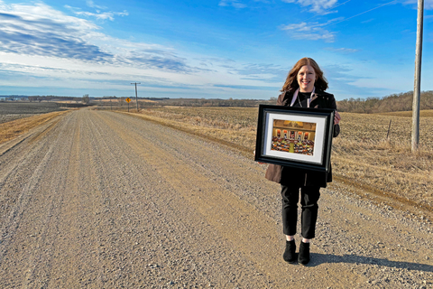 Amy Johnson se encuentra en un camino de grava sosteniendo una foto enmarcada.