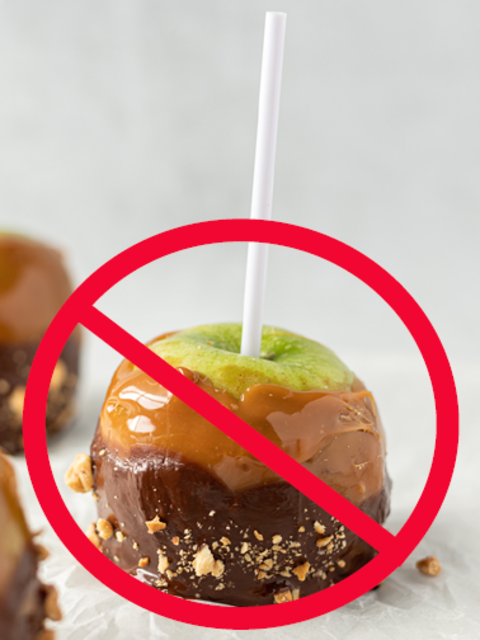 A caramel apple with a stick coming out the top and a red "no" symbol on top of it.