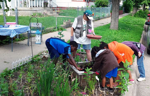 An Extension Master Gardner volunteer helping kids in St. Paul take care of a community garden.