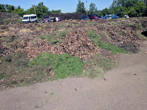 Cars parked along an embankment of lawn clippings and other debris.
