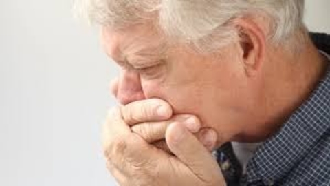 Man coughing with hands over his mouth.