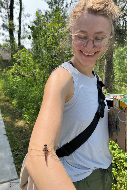 Myra McKee sonriendo ante una libélula que se posó en su brazo