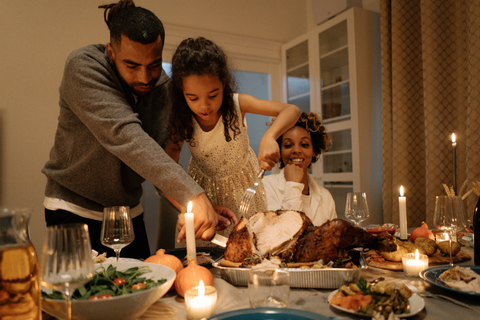 A father and daughter carving a turkey at a holiday meal