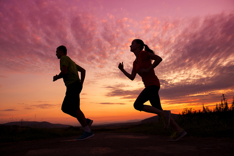 Man and woman running at sunset.