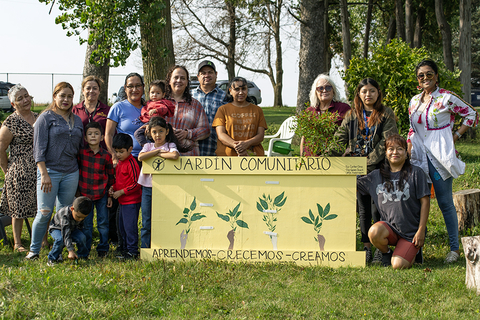 A large group of people posing behind the "gardin comunitario" sign.