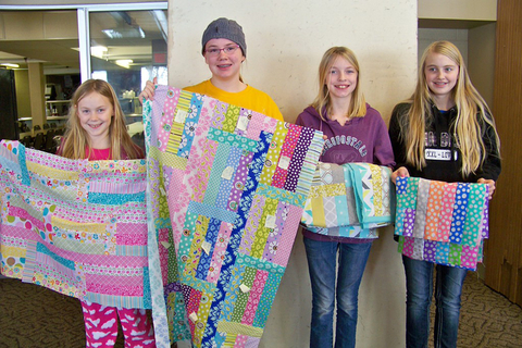 4 girls holding up their quilts