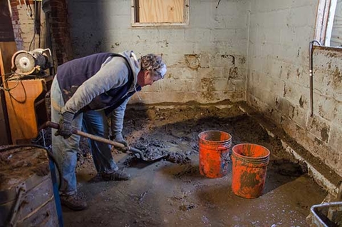 Removing mud from a basement after a flood.