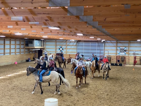 group of horses and riders in an indoor arena