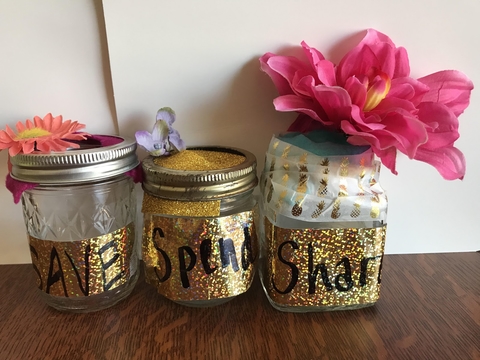 Three jars decorated with glitter and flowers, one says "save", one says "spend", and the last says "share". 