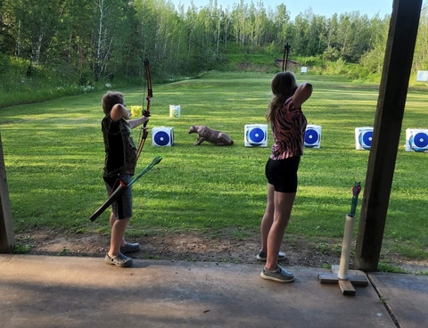 Youth holding bow and arrows aiming for targets.