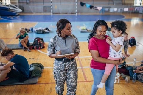 A female soldier in a gym taking a health survey with a mom and baby