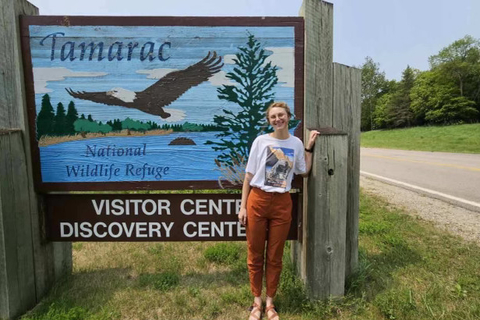 Myra McKee parada frente al cartel de bienvenida del Refugio Nacional de Vida Silvestre Tamarac