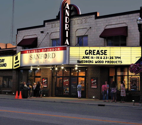 A movie theater at dusk with "Grease" on the display board.