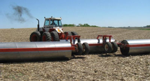 Tractor pulling equipment that has three large metal rollers and two sets of wheels.