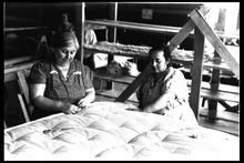 Two women sewing a mattress