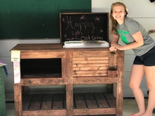 4-H youth standing next to a wooden sideboard