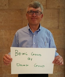 Kent Gustafson holding sign that says "Being good by doing good"