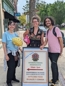 Mar Valdecantos, Andi Sutton and Jesus Valdez standing in from of a market sign.