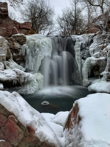 A photo of a waterfall in frozen winter landscape.