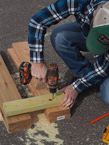 Person using a cordless drill to screw 2 x 4-inch leg connectors to 2 x 6-inch legs.