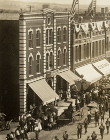 Black and white photo of The Grand Hotel in the early 1900s with many people in the street in front.