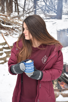 woman drinking hot chocolate by bonfire