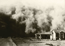 air filled with dust and dirt as it approaching two homes during the Dust bowl in the 1930s.