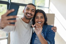 Happy couple taking selfie with new home key