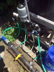A thick hose is interrupted by a series of connector pieces with smaller hoses that connect to a MixRite injector pump, which inserts fertilizer into the water stream.