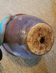 Ceramic pot with soil debris on bottom.