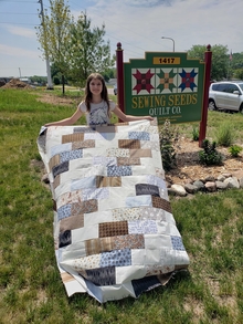Girl holding a quilt outside.