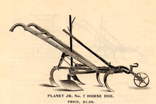 Old hoe equipment to be pulled by a horse. Two connected handles, five blades and one wheel in the front.