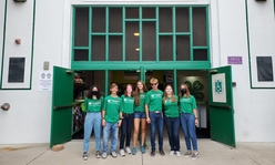 A group of youth standing in front of the entrance to the 4-H building on the Minnesota State Fairgrounds.