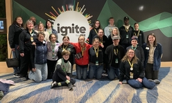 A group of youth and adults standing in front of a sign that says, "Ignite by 4-H."