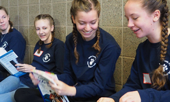 A group of smiling girls looking at workbooks.