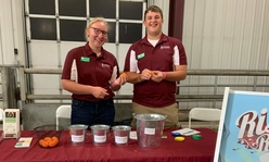 4-H ag ambassadors wearing maroon polos standing behind a table with an Extension logo.