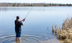 A boy fishing by a body of water.