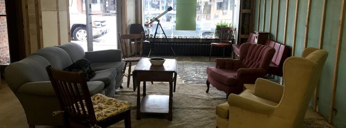 Room with couch and chairs and a microphone on a stand in the front.
