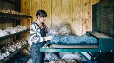 woman standing at wool processing machine