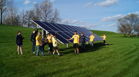 Group of people around a ground mounted solar panel.