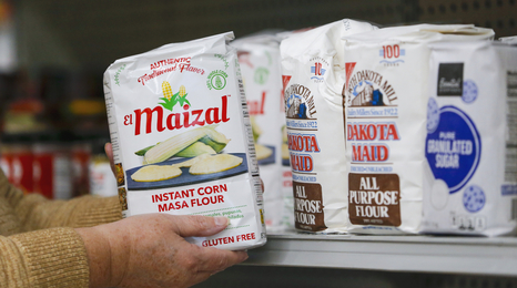 A person stocking masa flour at a food shelf