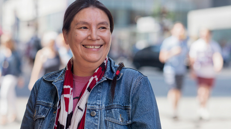 A Native American person smiling while standing in an urban area