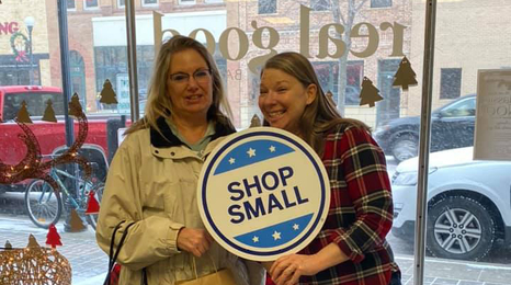 Two people inside a store holding a sign