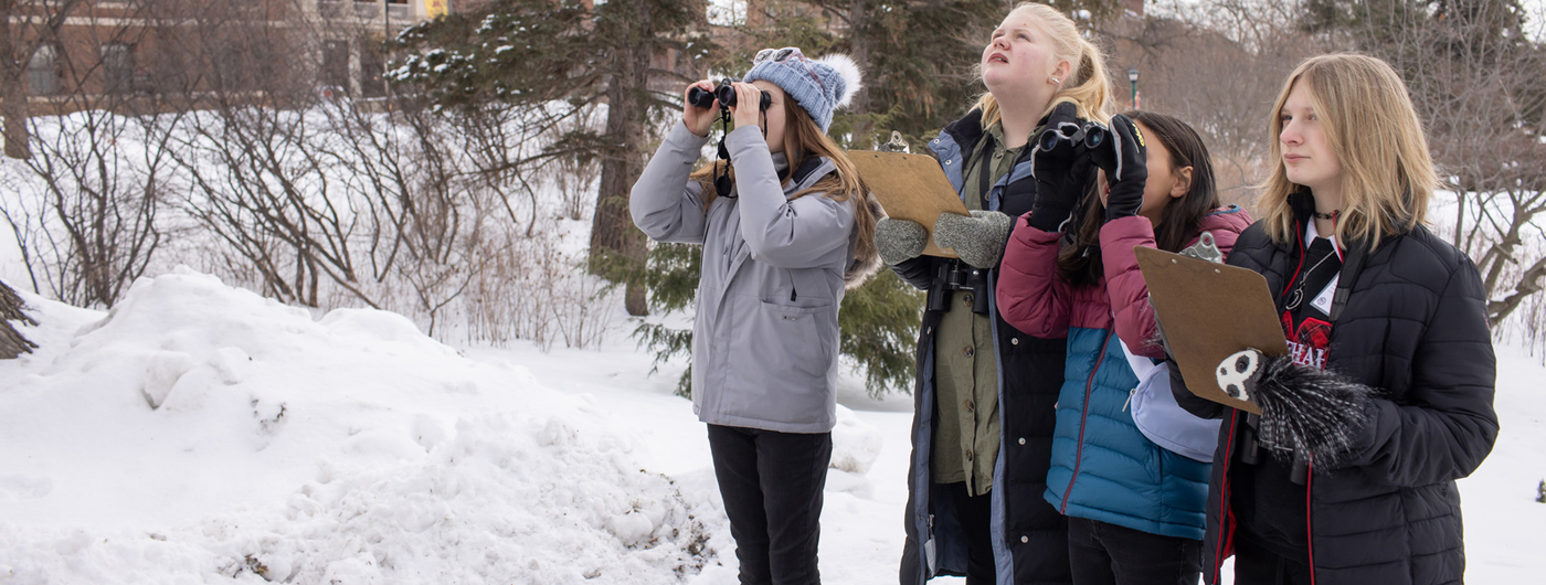 Students using binoculars outside in winter.